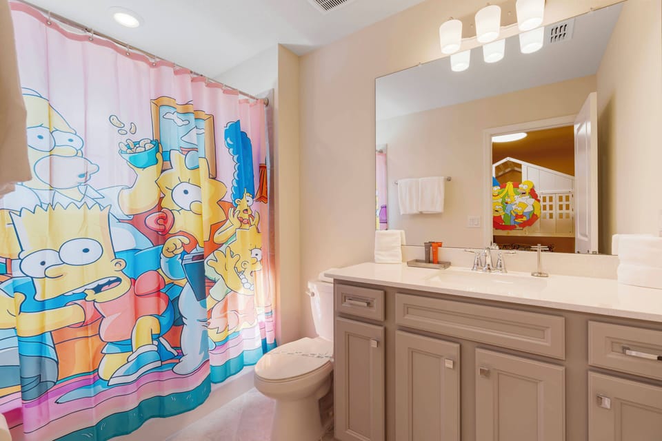 This bright and cheerful bathroom features a playful shower curtain with beloved cartoon characters, adding fun to your experience. The light cabinetry and spacious counter ensure both style and practicality for your stay.