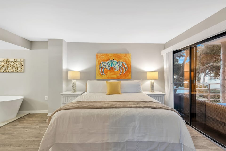 Bedroom 1 – Primary Suite: King-size bed with premium linens, Private balcony access with ocean and pool views, Ensuite with stand-alone soaking tub and walk-in shower, and a 65" smart TV