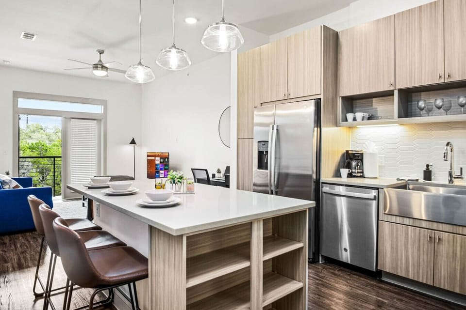 Prepare meals in this modern, fully-equipped kitchen featuring stainless steel appliances and a spacious island with bar seating. The open layout makes it easy to cook and entertain, ensuring a delightful culinary experience during your stay.