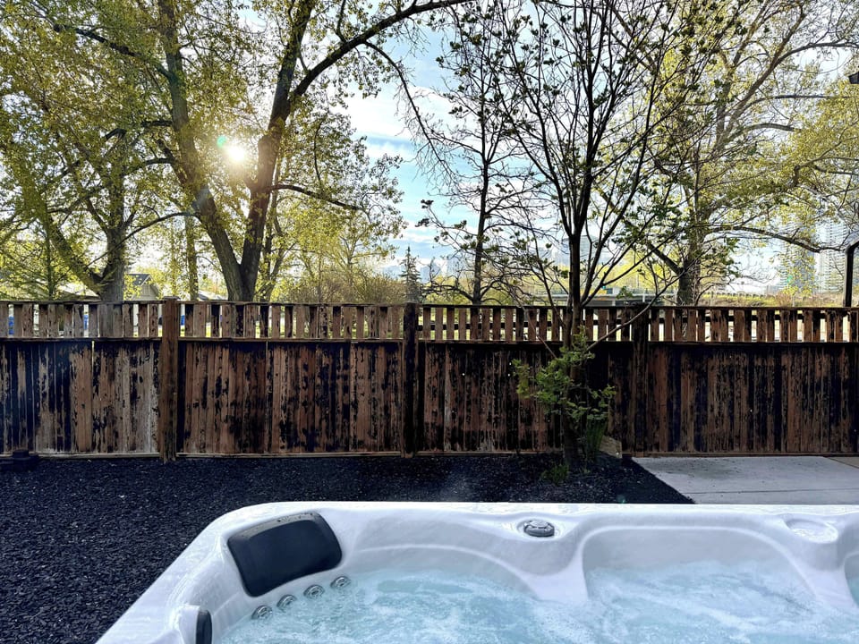 Large 8+ person hot tub nestled in the backyard with green space views - quiet, tucked away, and extra private under the trees.