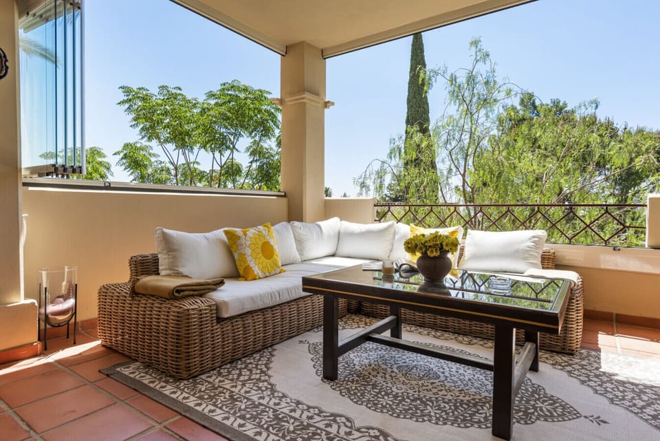 Sunny terrace with chillout seating area, dining area, Lumon glazing, and partial sea views