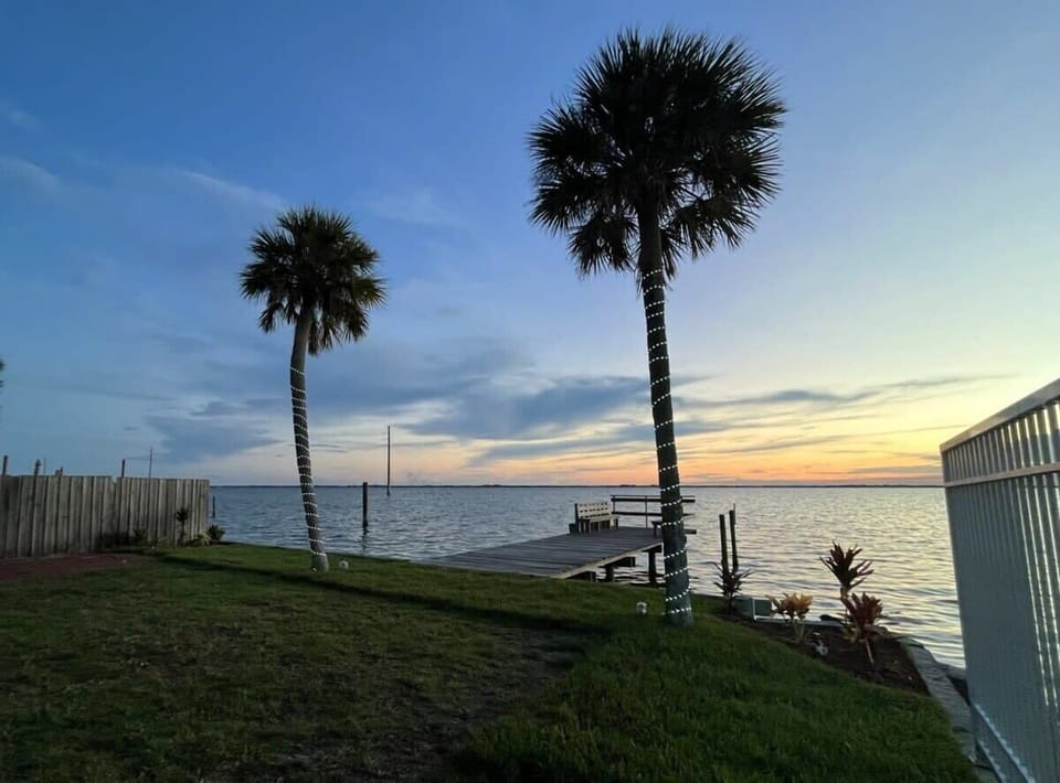 Relax by the waterfront dock framed by palm trees at sunset.