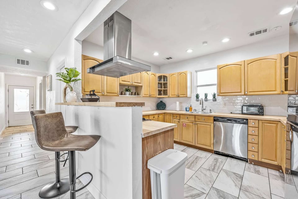 Modern kitchen with wooden cabinets, stainless steel appliances, and a breakfast bar with seating.