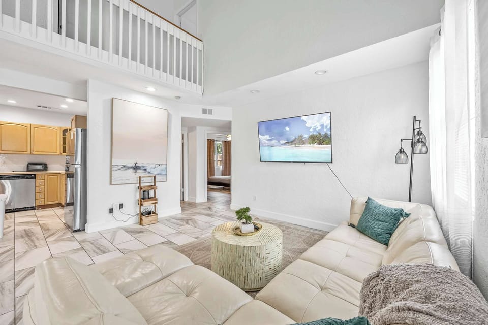 Bright living room with vaulted ceilings and a modern leather sectional sofa