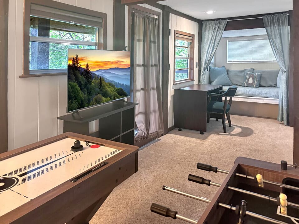 The lower-level has a separate entrance and includes an air hockey table, foosball, large Smart TV, separate mini-fridge/microwave/Keurig, a twin day bed, and a desk for remote work. There is also patio seating on the lower deck.
