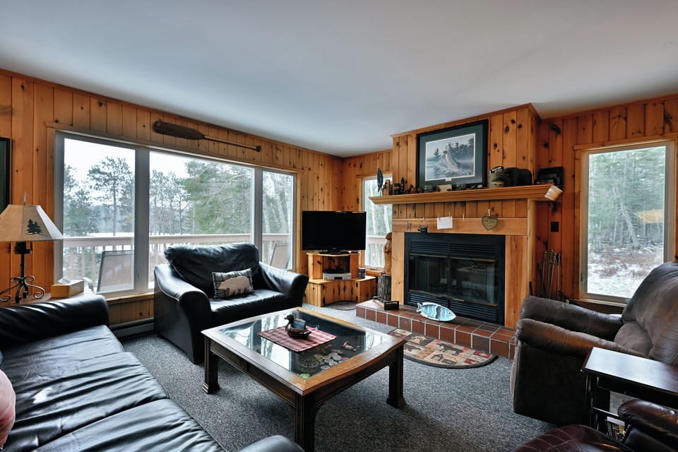 A spacious living room with high ceilings, a  fireplace, and breathtaking lake views.