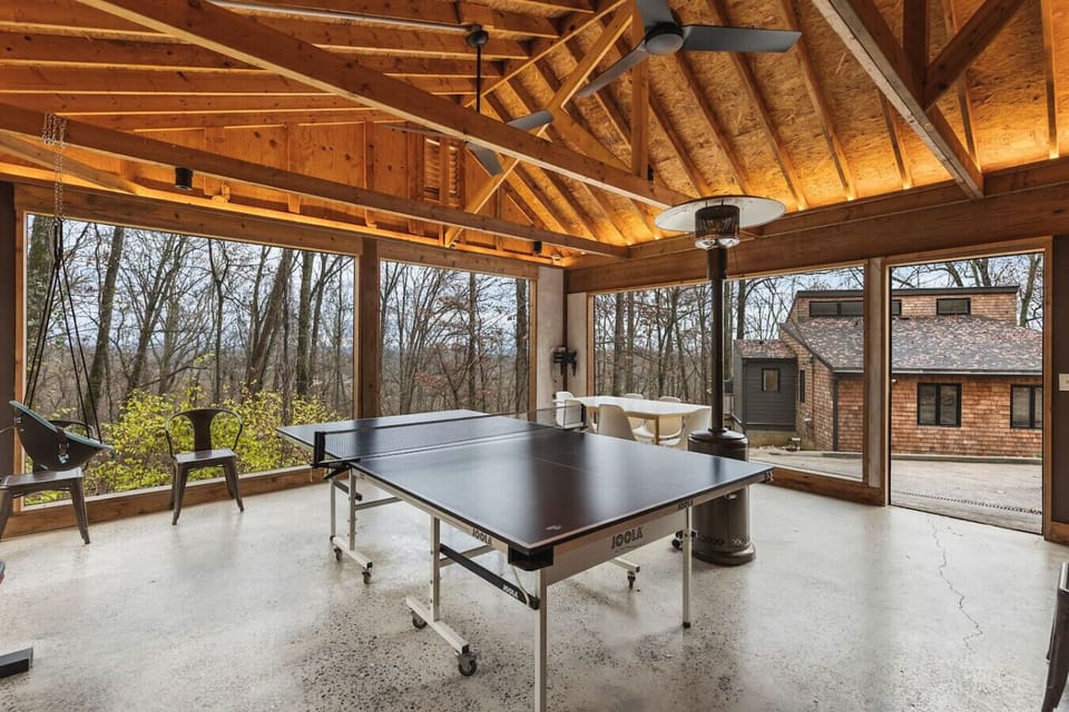 Game room with a ping pong table, kid's swing, boxing bag and weights, and a table for dining or playing games.
