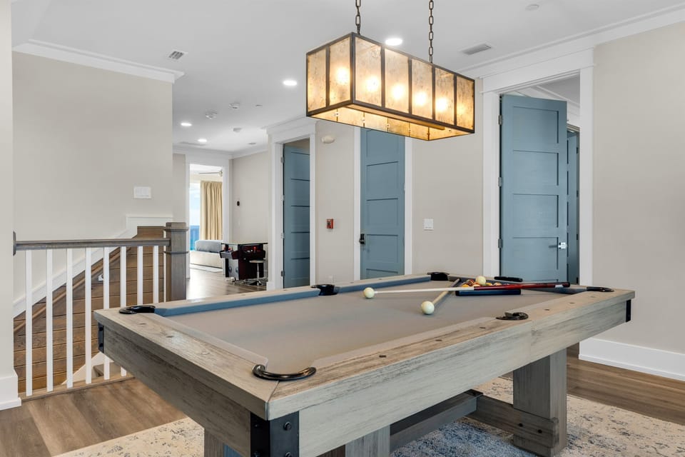 Challenge your friends to a game of pool in this stylish upstairs game room, where the rustic table meets modern elegance.