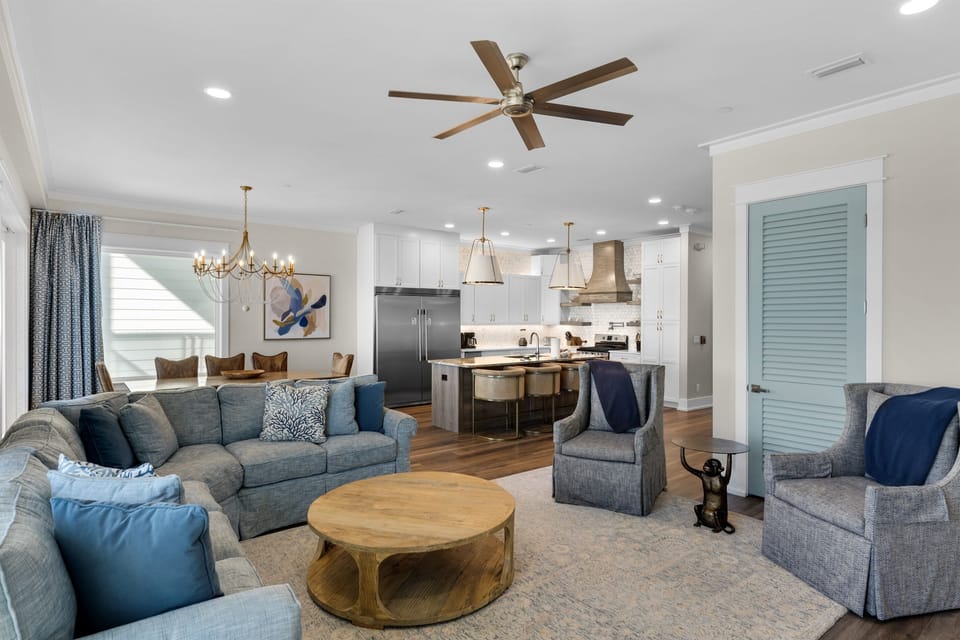 Sink into plush gray sofas with ocean-blue accents in your open-concept living space, where coastal elegance meets modern comfort.