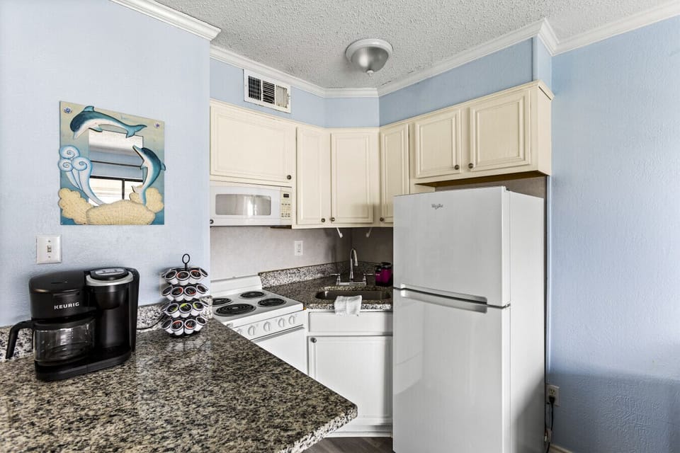 Bright kitchen with granite countertops, Keurig coffee maker, and cozy decor.