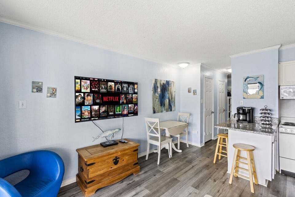 Dining and kitchen area with a smart TV, coffee station, and bar stools