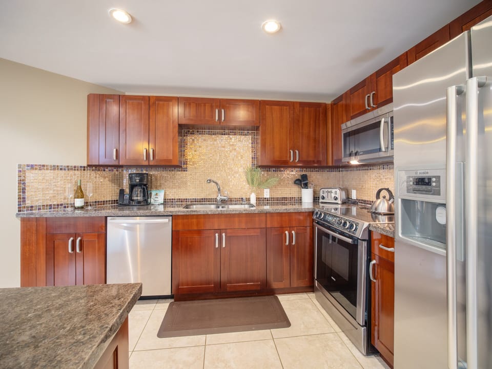 Cook up delicious meals in this fully equipped kitchen, featuring stainless steel appliances and elegant granite countertops.