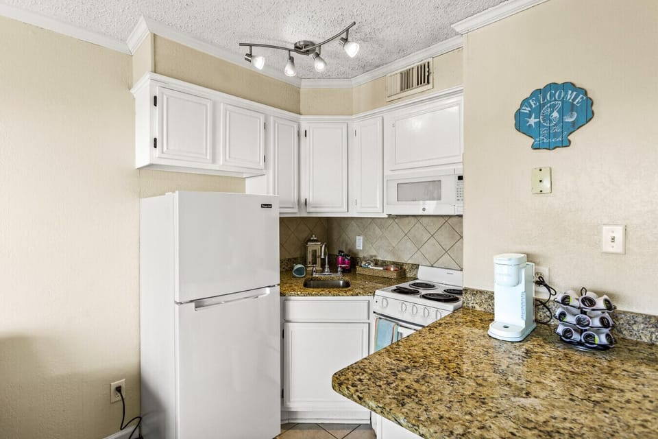 Granite countertops with a stainless steel sink and soap dispenser.
