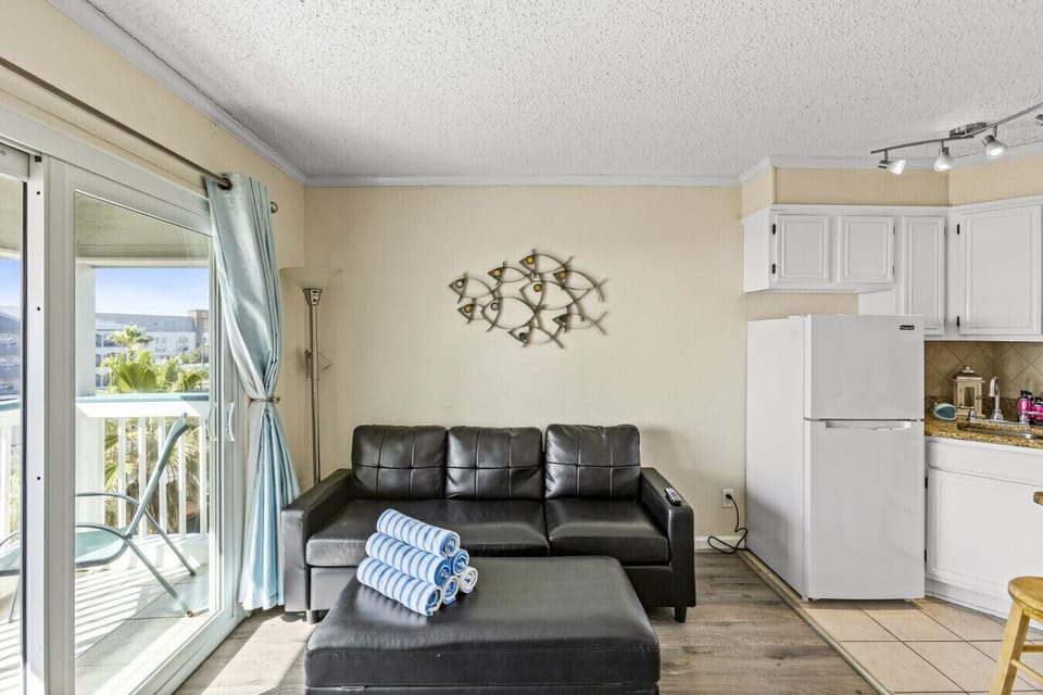 Cozy seating area with balcony access and a fully equipped kitchen nearby