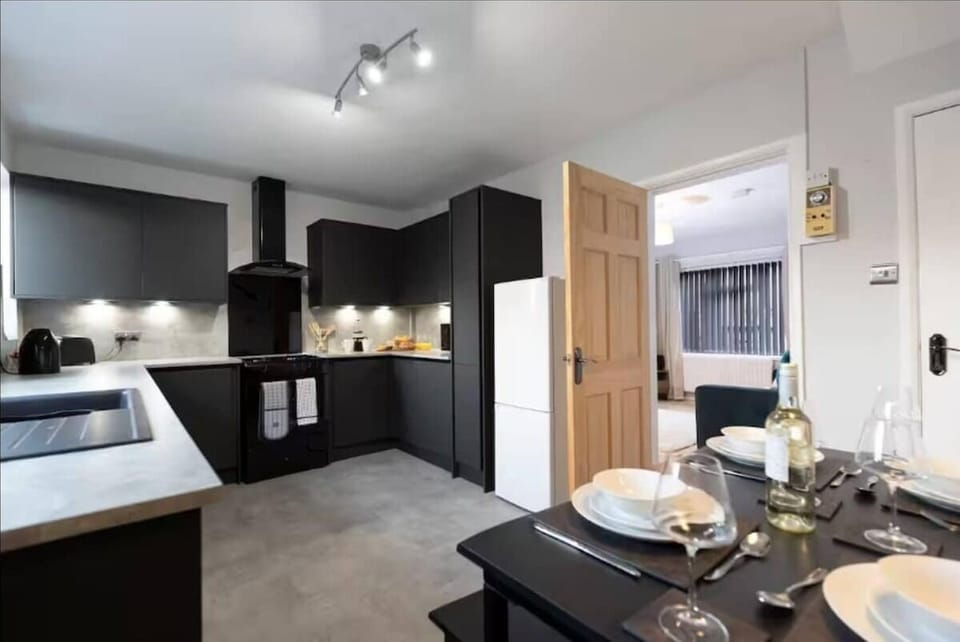 Enjoy a modern, fully-equipped kitchen with sleek black cabinetry, ample counter space, and a cozy dining area set for four—perfect for home-cooked meals and gatherings.