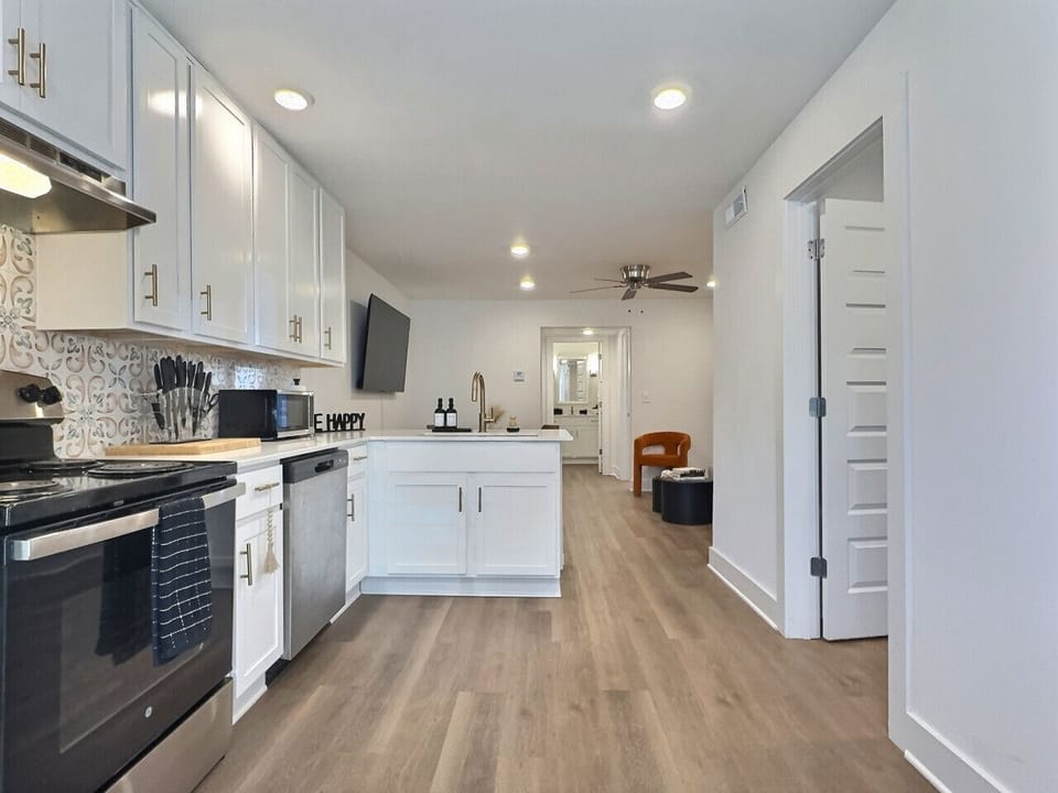 This kitchen features elegant white cabinetry complemented by chic gold hardware, offering a fresh and contemporary look.