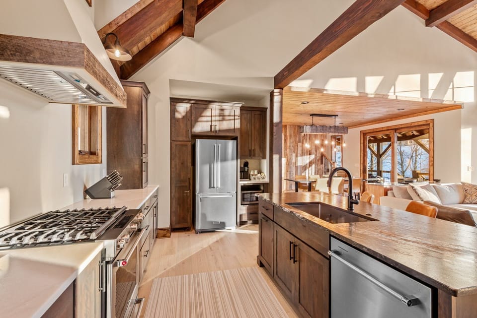A chef-ready kitchen with soaring beam ceilings and a live-edge island, opening right into the living space at Roll Out The Barrel At Eagles Nest.
