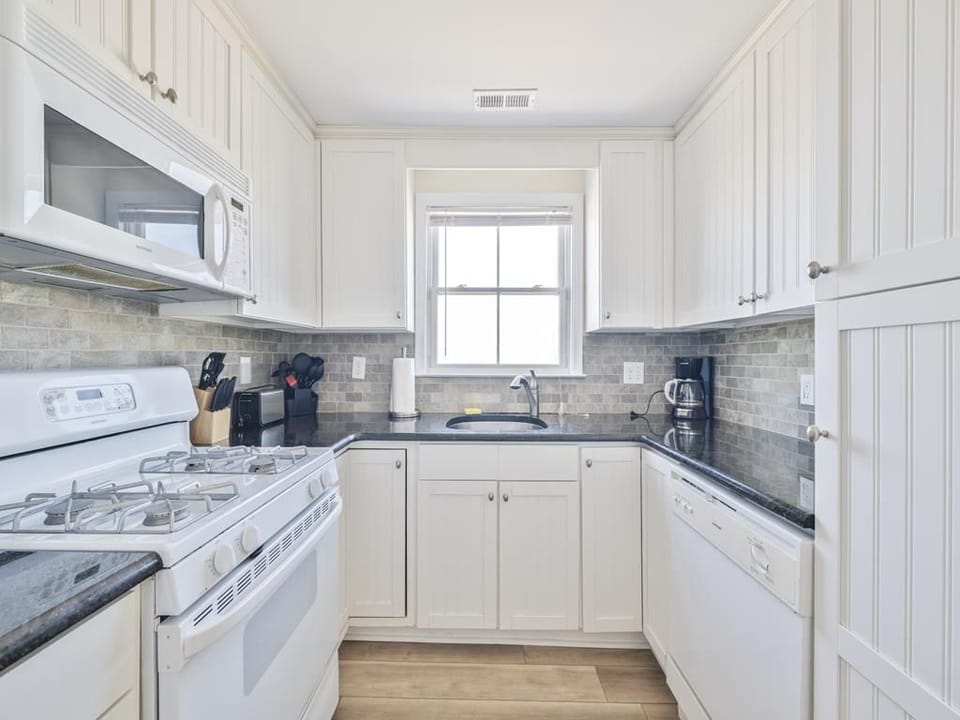 Enjoy cooking in this chic kitchen, where sleek countertops meet sunlight pouring through the window.