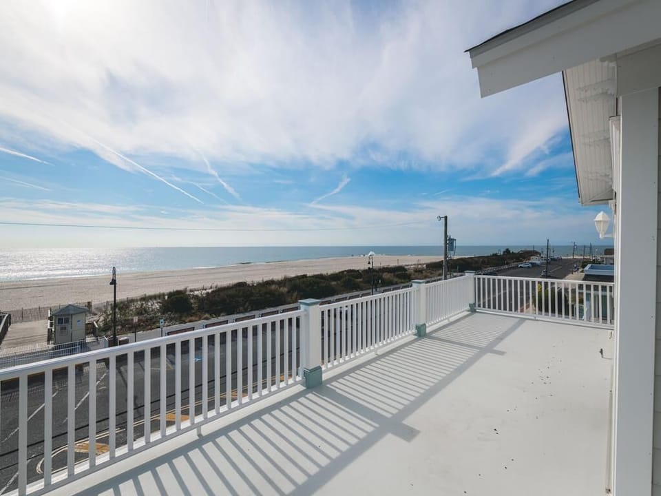 A breathtaking ocean view from the condo's spacious deck, where the shimmering waves meet the sandy beach under a bright blue sky.