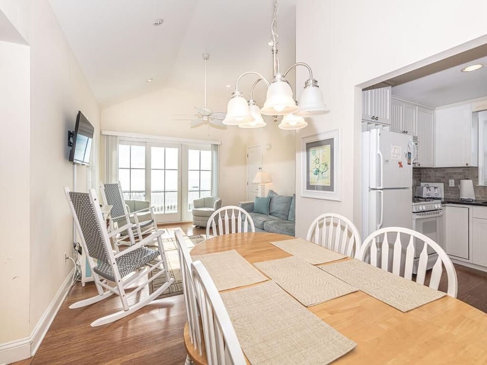 Bright open-concept dining and living area featuring coastal décor, comfortable seating, and large windows that fill the space with natural light and ocean views.