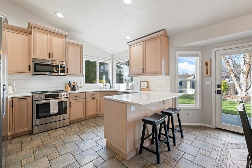 The kitchen is a chef's dream, featuring sleek Bosch appliances, a 5-burner gas stove with convection and a warming drawer, and stunning white quartz countertops. A breakfast bar provides additional seating, perfect for casual meals or entertaining.