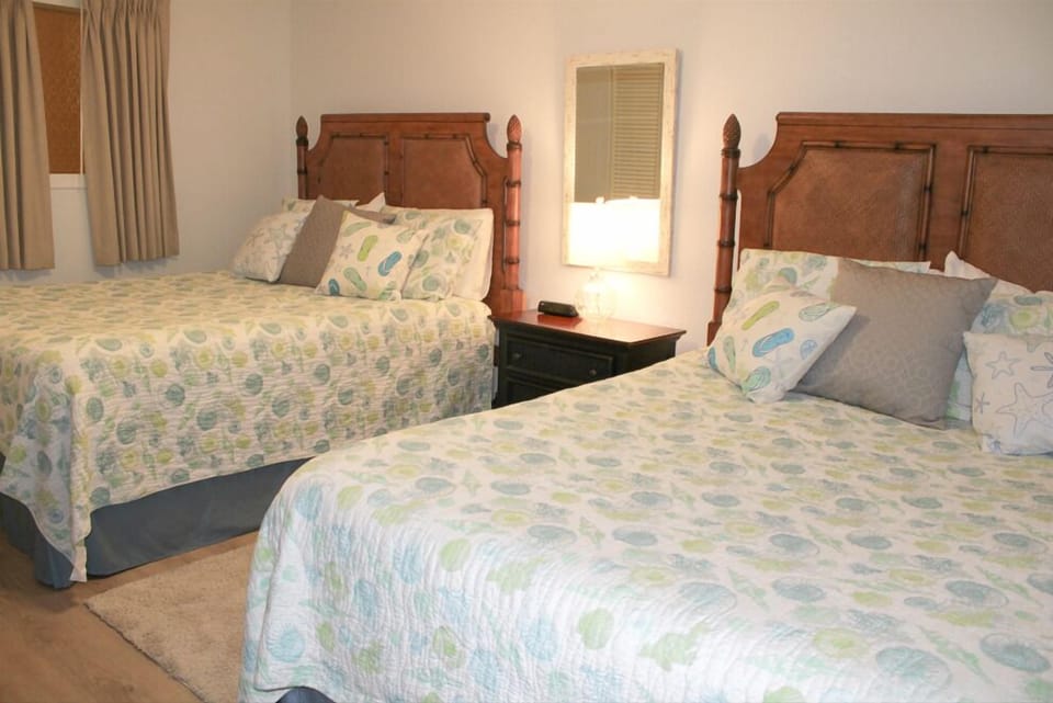 Rest peacefully in your comfortable twin bed setup, featuring tropical-inspired linens and warm wooden headboards that create a cozy, island-style retreat.
