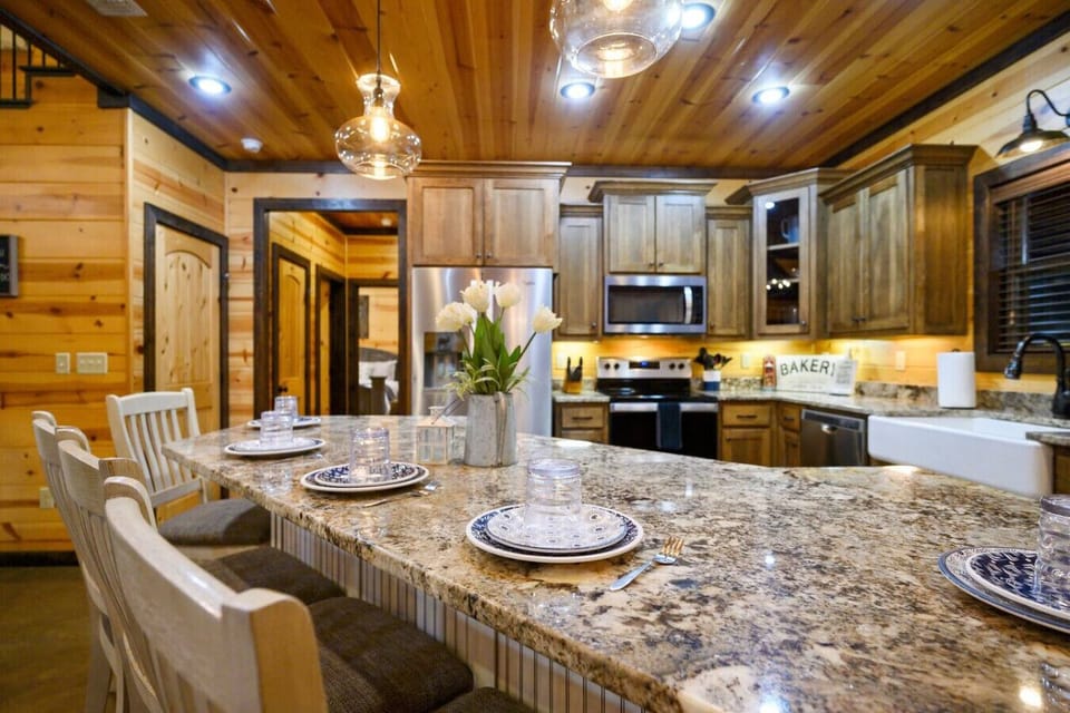 This granite island is long enough to gather everyone around for a meal, with that warm under-cabinet lighting and the full kitchen stretched out behind it—basically the heart of the whole place where people actually want to hang out.