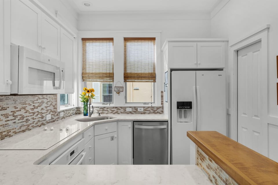 Your fully equipped kitchen gleams with white cabinetry, marble counters, and modern appliances—perfect for preparing meals during your stay.