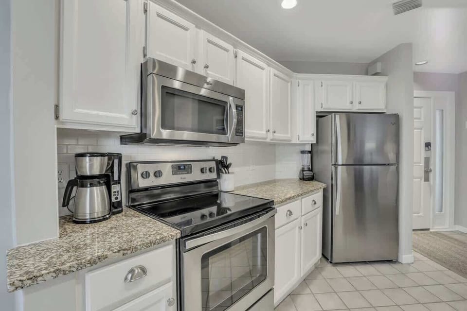 A clean, functional kitchen equipped with bright white cabinetry and granite countertops.