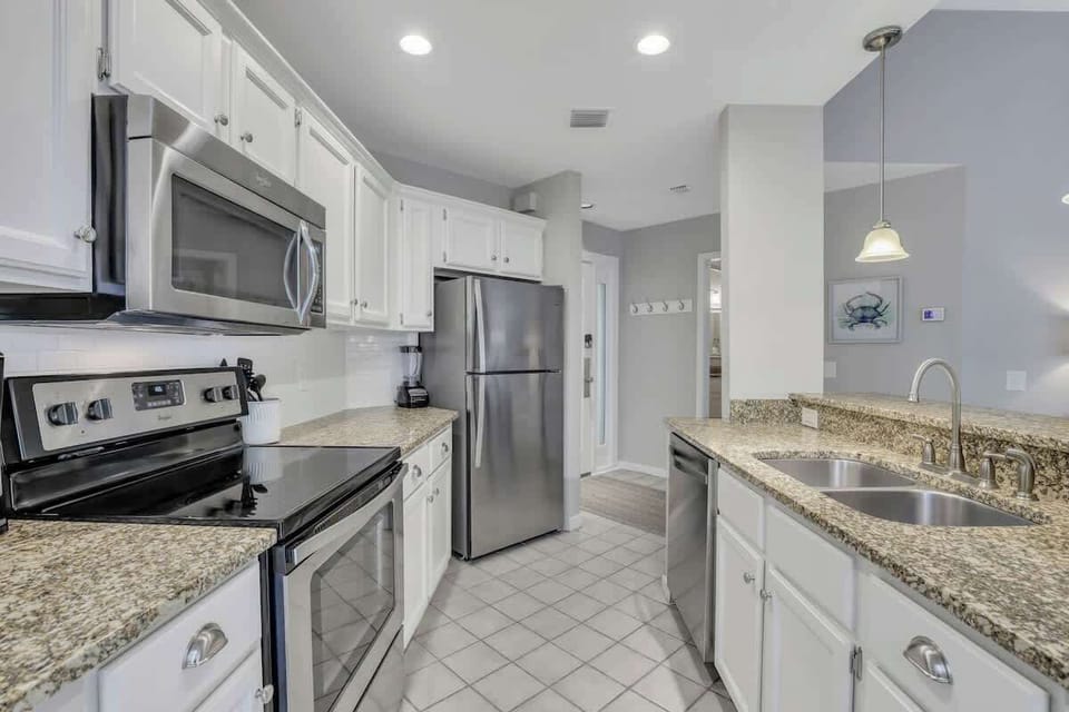 Spacious open kitchen with full appliances, tile floors, and bright lighting.