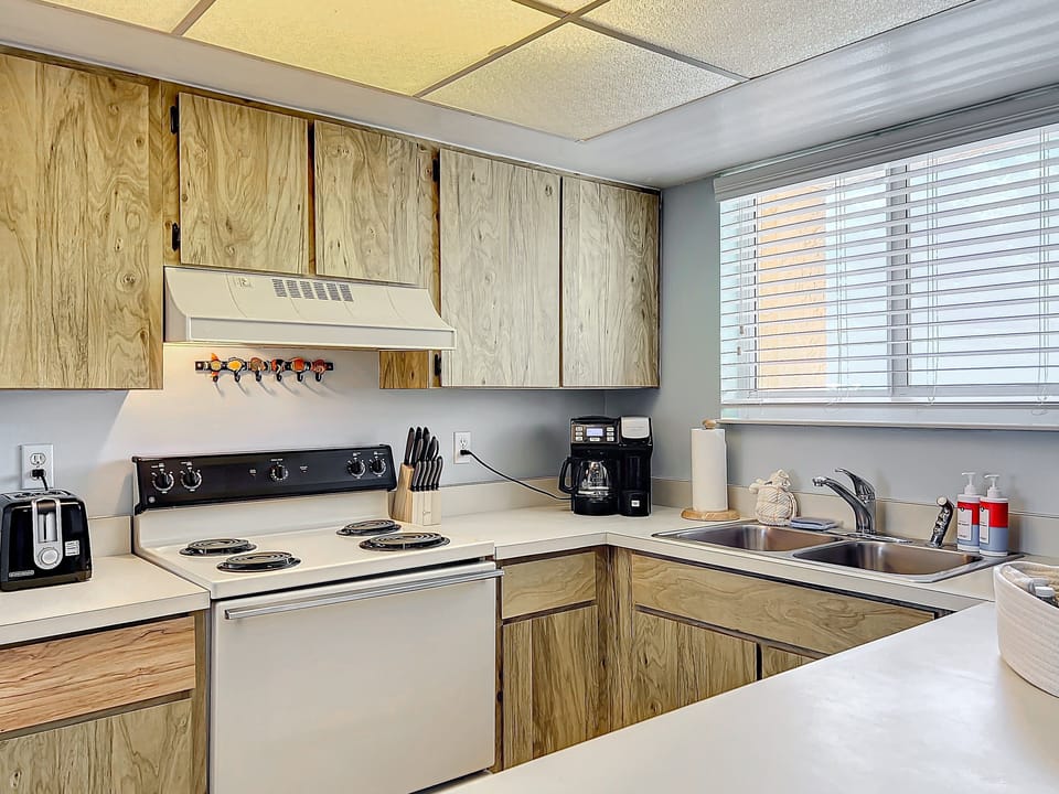 This inviting kitchen offers everything you need, including a stovetop, toaster, and coffee maker, complemented by natural light and a cozy atmosphere.