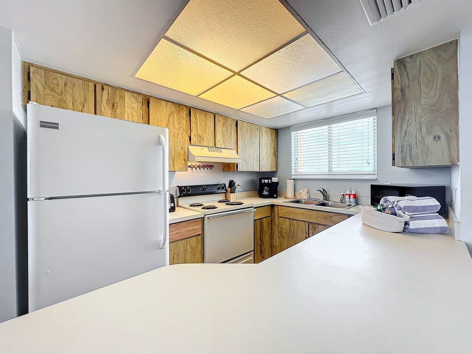 Prepare meals with ease in this well-lit kitchen featuring modern appliances, ample counter space, and a charming coastal vibe.