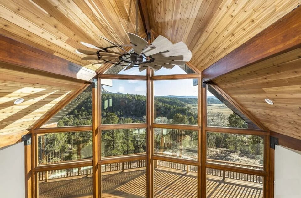 Stunning vaulted ceiling with wooden accents and expansive windows showcasing panoramic views.