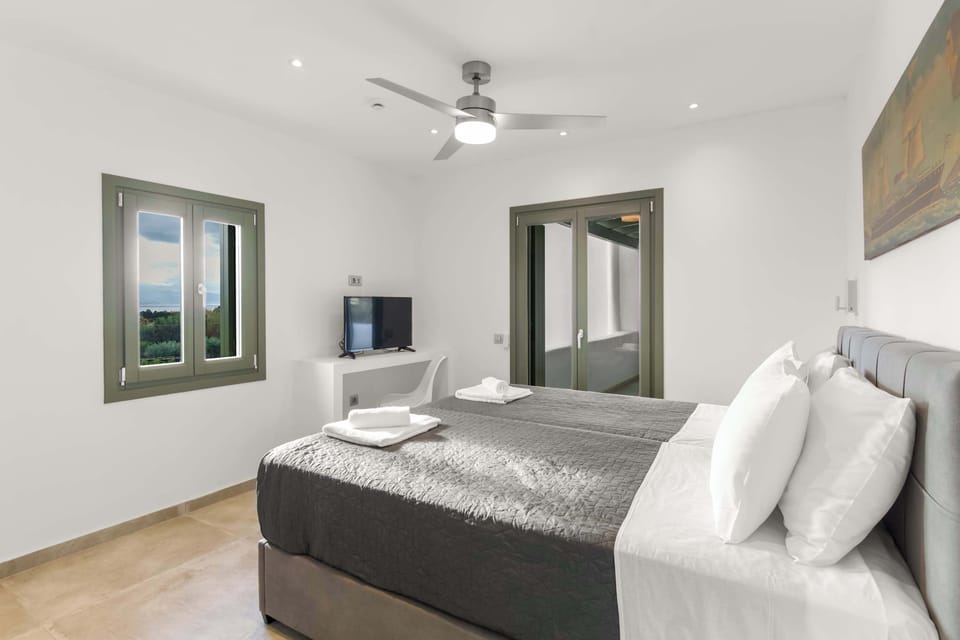Twin Bedroom – Minimalist and Comfortable
Neutral tones, ceiling fan, and green window shutters for island charm.