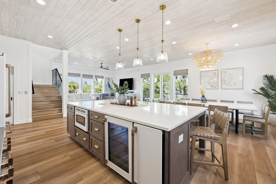 Gather around the bright, open kitchen island overlooking a spacious dining area—perfect for morning coffee and shared meals in coastal comfort.