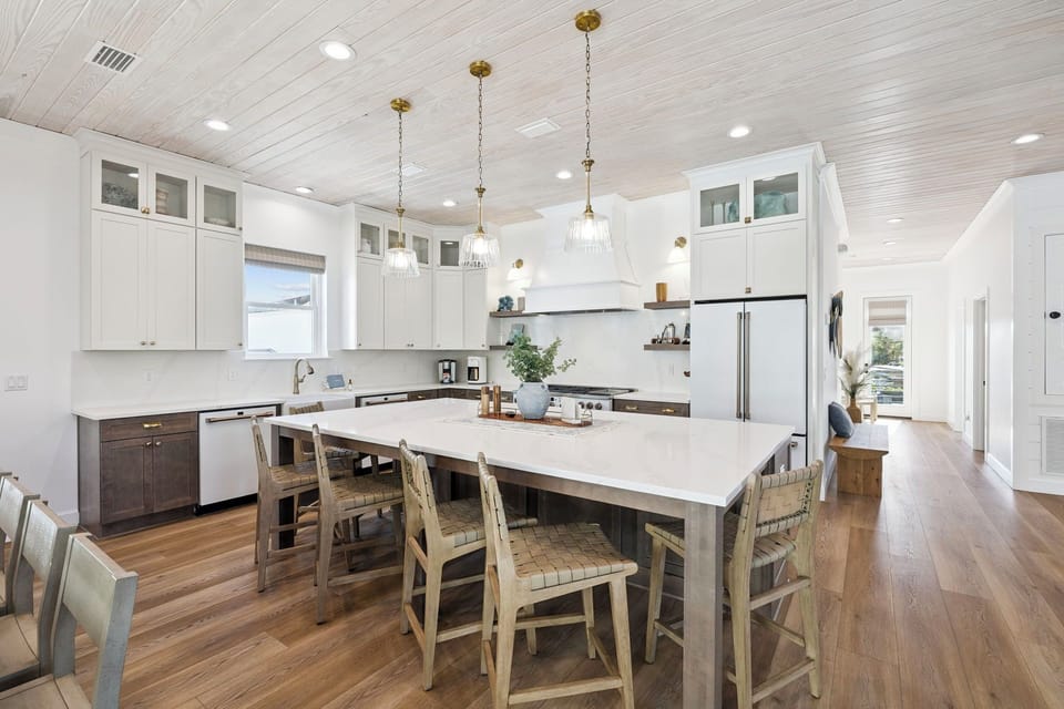 You'll love gathering around this spacious kitchen island, where sleek white countertops and warm wood tones create a welcoming heart for your vacation home.