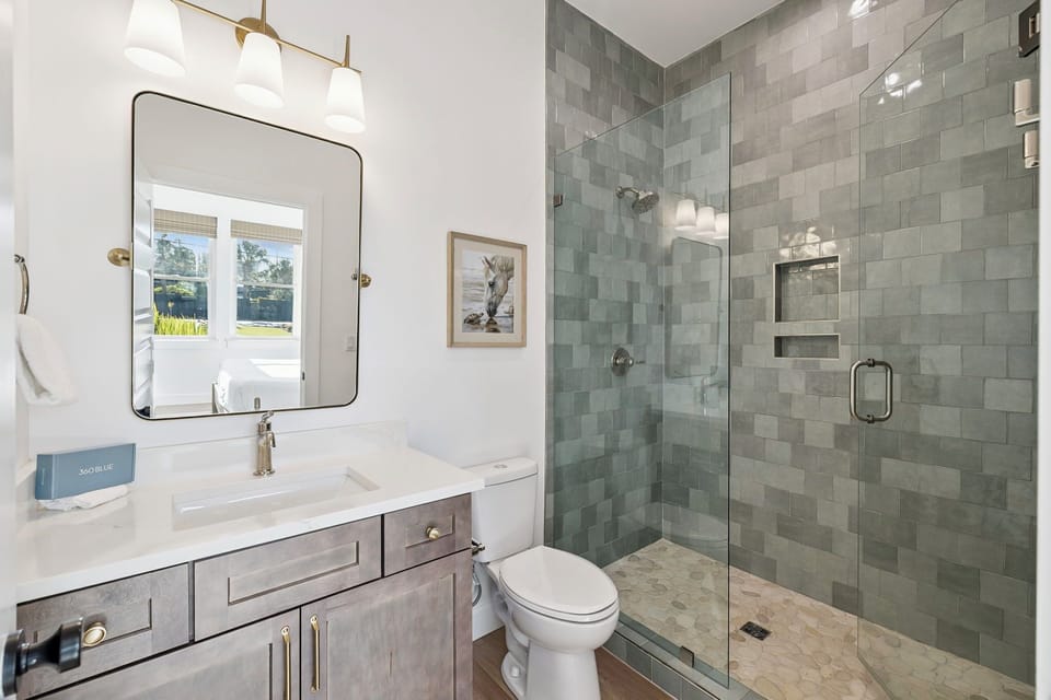 Step into your spa-inspired retreat where calming subway tiles and a spacious walk-in shower await. Natural light pours through the window, warming clean lines and creating your perfect sanctuary for unwinding after a day of adventure.