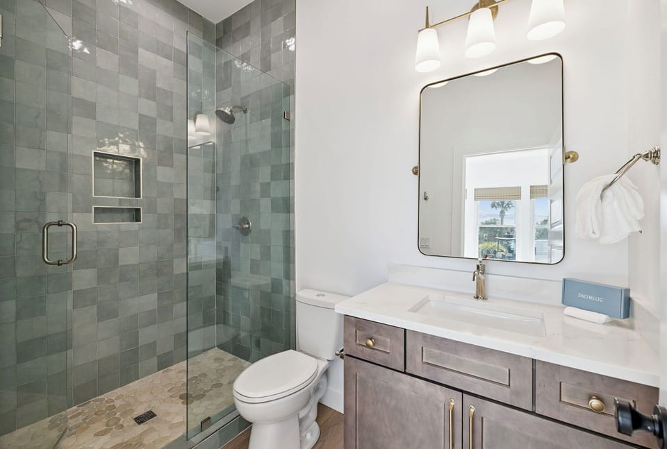 Refresh and unwind in your elegantly tiled bathroom, featuring a spacious walk-in shower, modern vanity, and soothing coastal-inspired design touches.