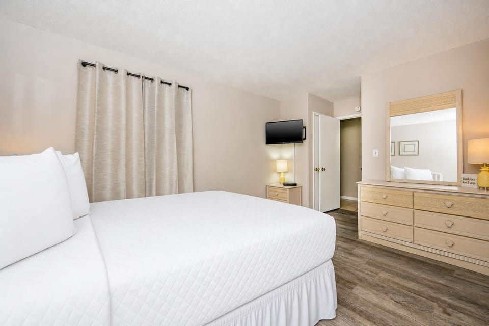 This cozy bedroom features a comfortable bed, a mounted TV, and soft beige tones, creating a relaxing retreat for guests