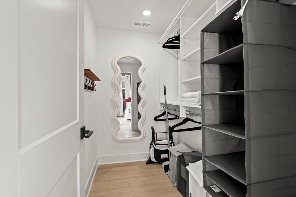 Closet area with full-length mirror, hangers, and hooks.