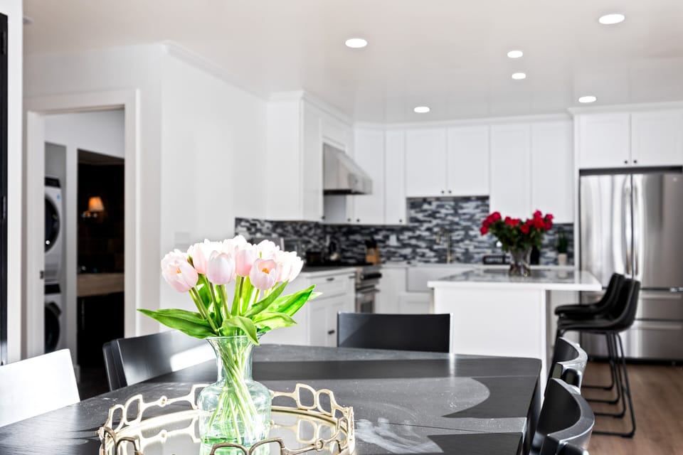 - Fresh tulips on dining table create welcoming alpine dining vibe  
- Open plan layout connects kitchen with spacious dining area  
- Natural light enhances modern black furniture and decor touches