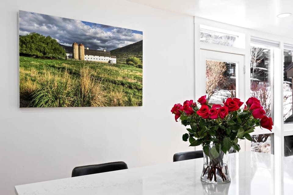 - Vibrant roses add warmth to the bright dining and kitchen area  
- Large wall art with mountain views creates alpine atmosphere  
- Open layout with natural light perfect for gathering together