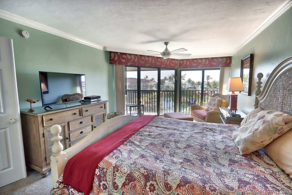 King bed with ensuite access to both the patio and primary bathroom, which features a large vanity and renovated walk-in shower.