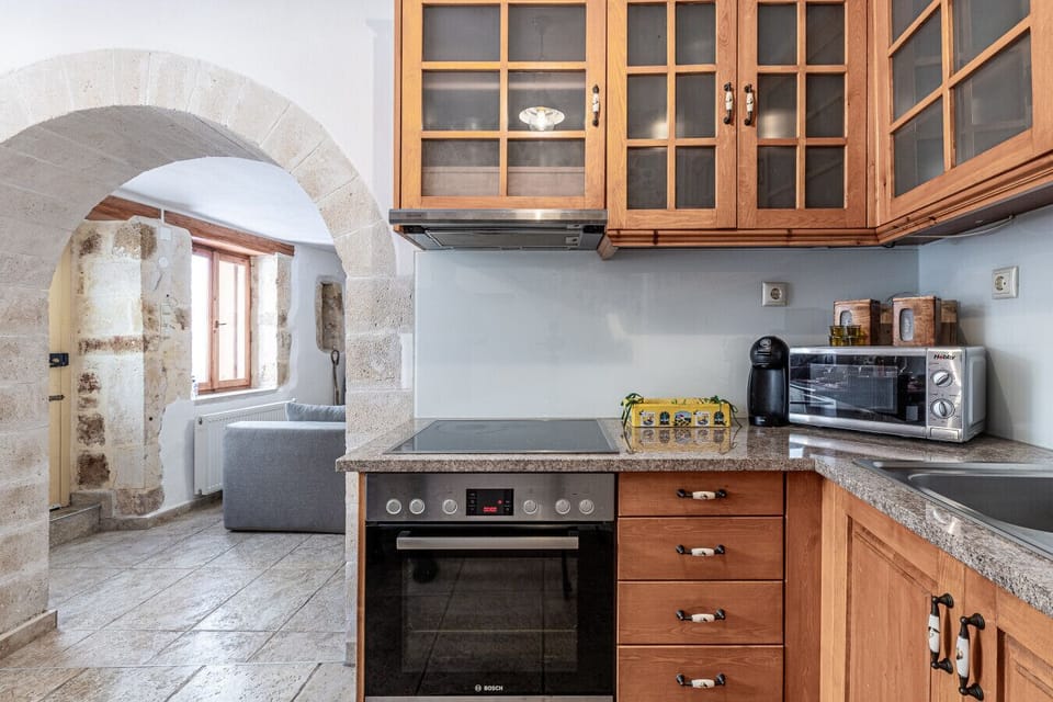 The kitchen of Casa Eleni features a fully equipped cooking space, a refrigerator, and a dining table with four seats, offering both functionality and comfort.