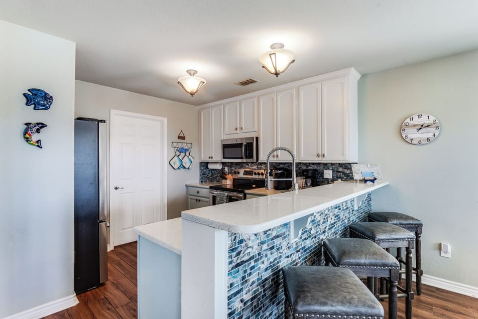 Your stylish kitchen features white cabinets, stunning blue mosaic tile work, and a breakfast bar perfect for morning coffee.
