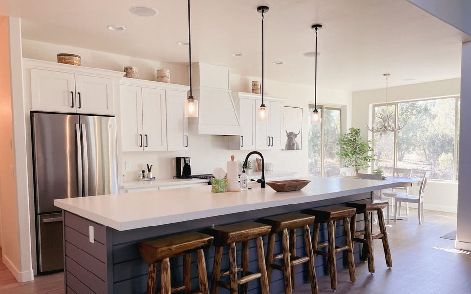 Gather around the oversized island in this modern kitchen—complete with rustic bar stools, stainless steel appliances, and plenty of natural light.