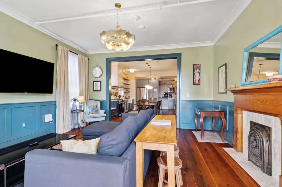Living room with a comfortable couch, smart TV, and a small workspace with a desk and chair — perfect for relaxing or getting work done.