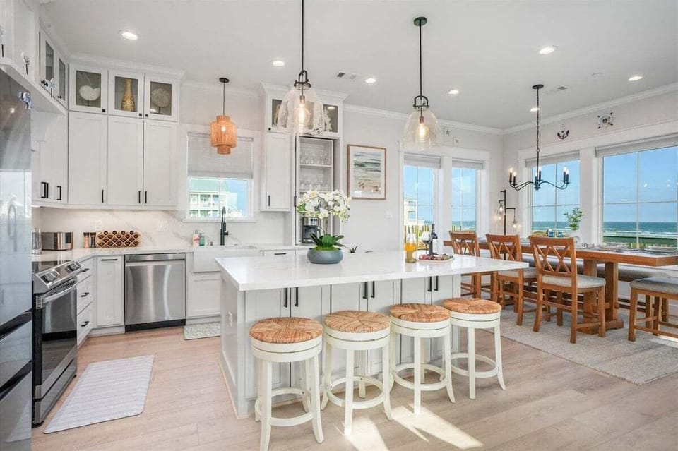 Open kitchen and dining layout with large island seating, modern lighting, and spacious entertaining area near the beach.