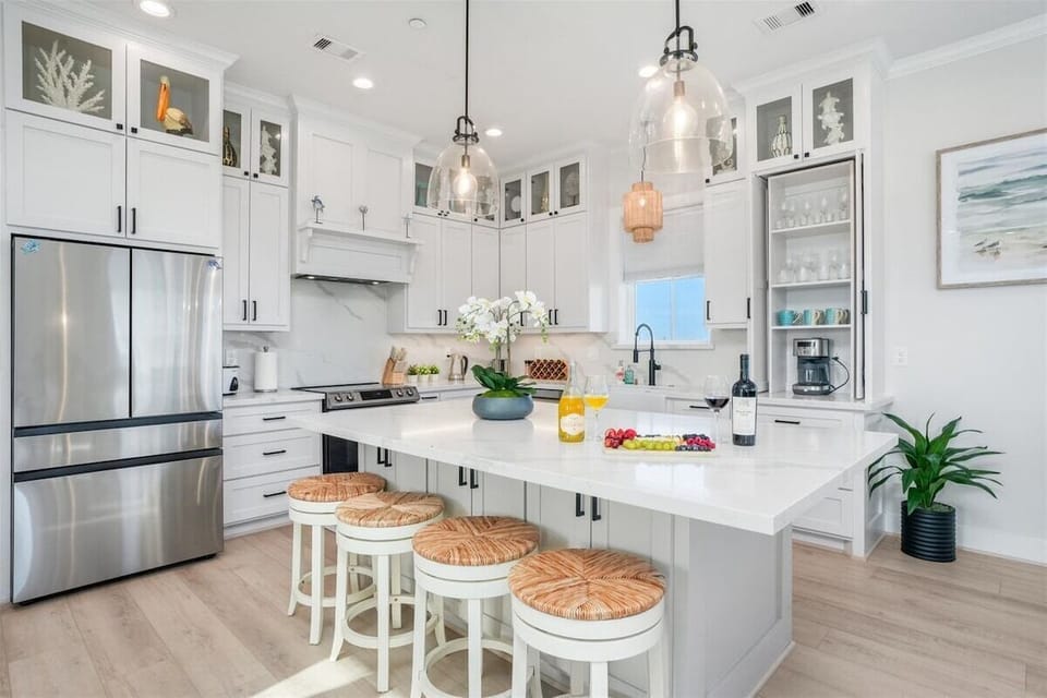 Luxury chef's kitchen with oversized island, stainless steel appliances, pendant lighting, and bar seating for large groups.