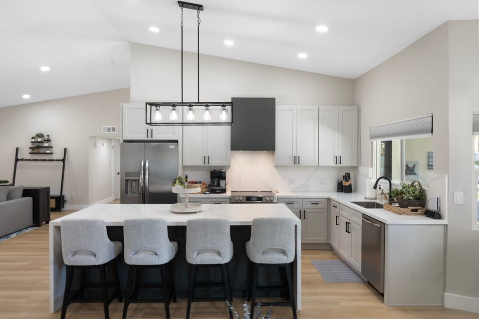 Modern kitchen with stainless steel appliances, island seating for four, and pendant lighting.